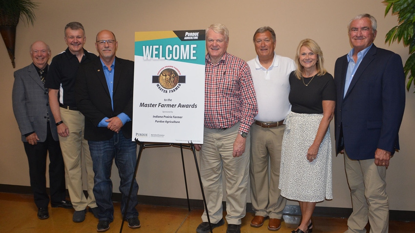  A group of people posing next to a welcome sign for the Master Farmer Awards