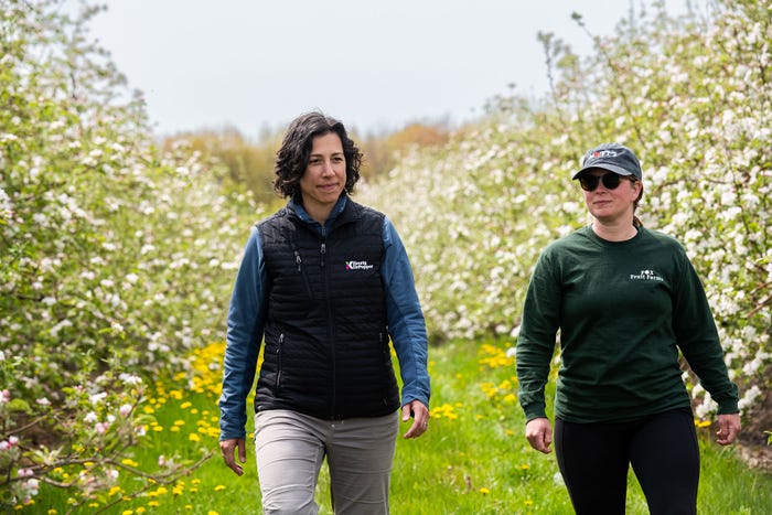 Keurig-Dr. Pepper - Whitney Kakos, director of supply chain sustainability at Keurig-Dr. Pepper walking with another woman through an orchard