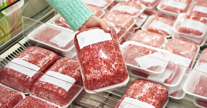 Customer at grocery store in meat department holding ground beef