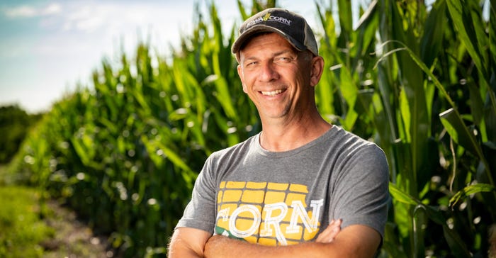 Man standing in front of corn field wearing T-shirt that says corn