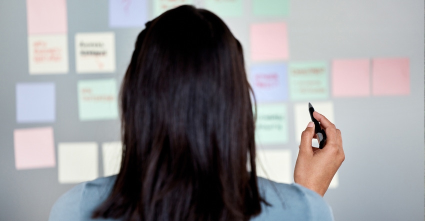 Woman writing on sticky notes on board