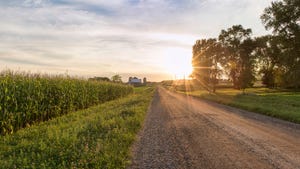 Rural sunset on gravel road with farm.