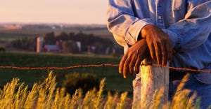 Hands of Farmer Leaning on Fence Post