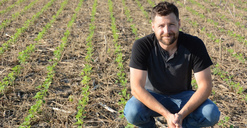 Jason Chatterton squats in no-till soybean field