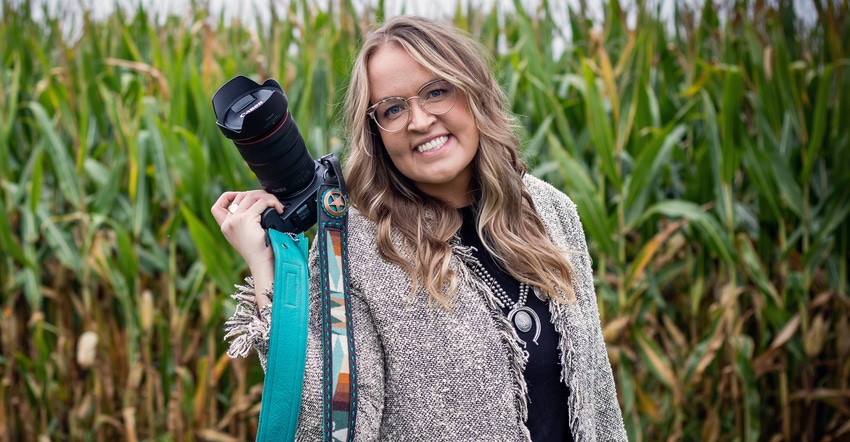Betty Haynes posing with camera in hand against cornfield backdrop 