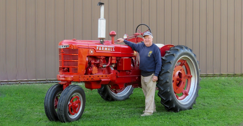 Lester Schuett stands next to a 1939 model Farmall H tractor