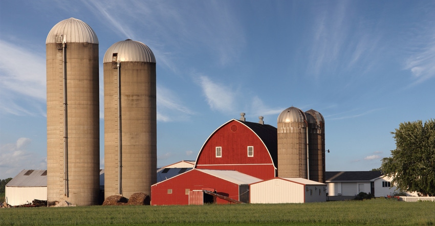 red barn next to two silos silos