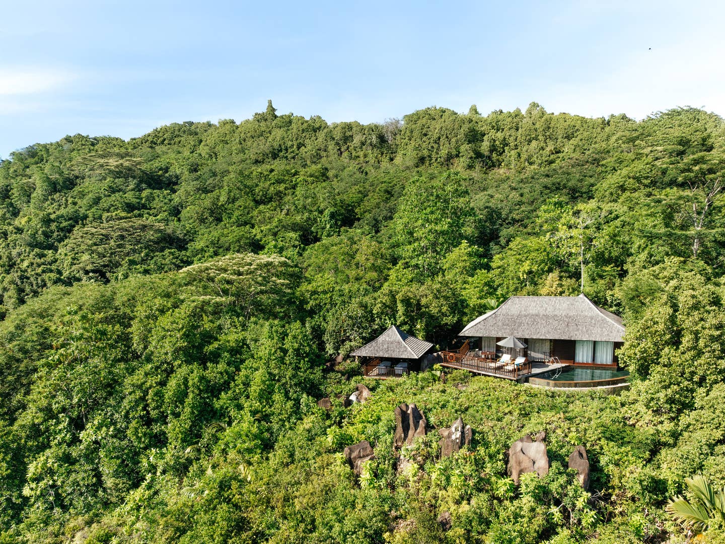 Eine Villa vom Constance Ephelia Resort auf den Seychellen inmitten einer bewaldeten Bergkette