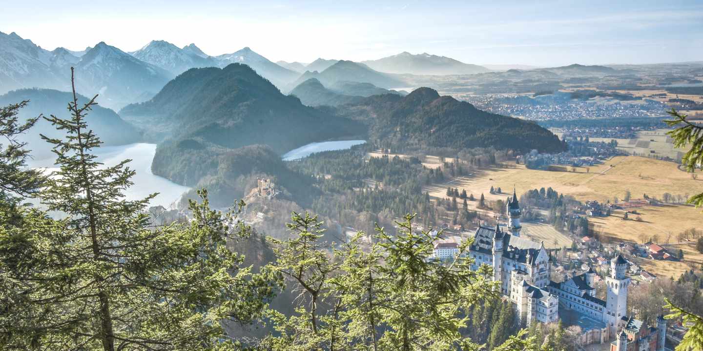 Reisetipp für Deutschland: Schloss Neuschwanstein umgeben von grünen Wäldern und Alpengipfeln im Allgäu