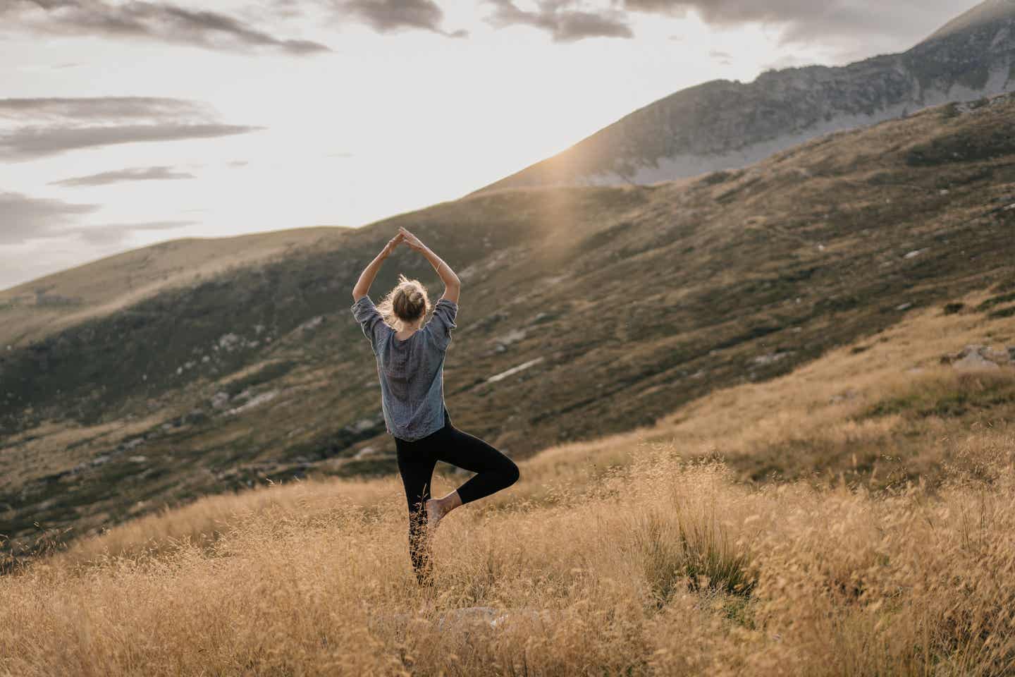 Tegernsee Urlaub mit DERTOUR. Frau beim Yoga in den Bergen bei Sonnenaufgang