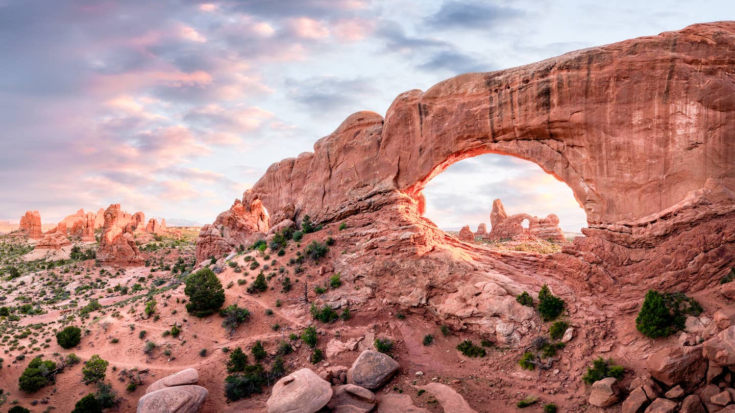 Blick auf Turret Arch durch einen Felsbogen im Arches-Nationalpark in Utah bei Abendlicht