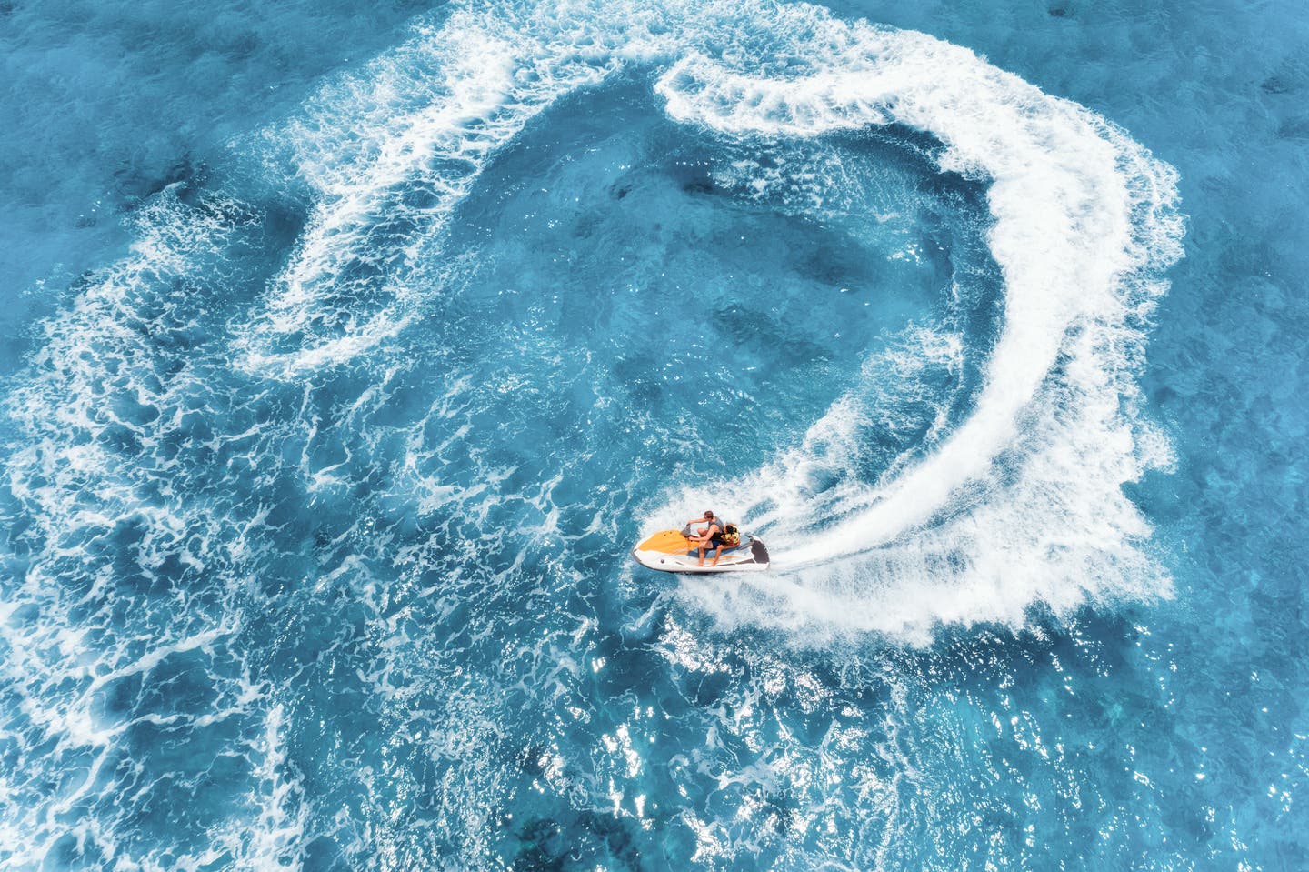 Wassersport beim Inselhopping in Griechenland: Jetskis parken am Strand im Wasser mit sanften Wellen