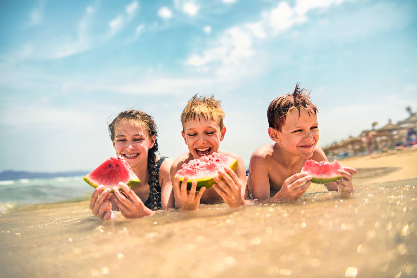 Im Spanien-Familientrip teilen sich Kids am Strand eine Wassermelone