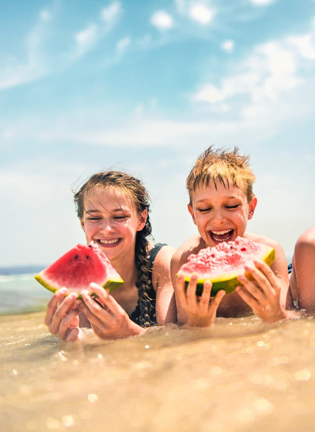 Familienurlaub All Inclusive Im Spanien-Familientrip teilen sich Kids am Strand eine Wassermelone