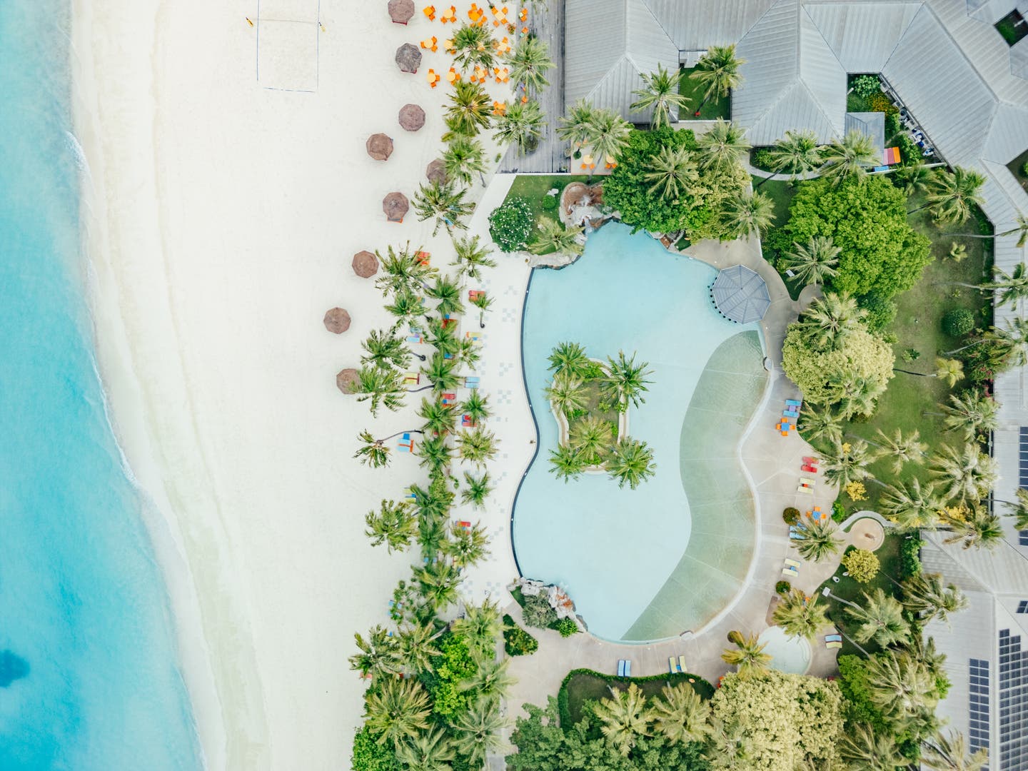 Topshot einer Drohne auf den Hotelpool am Strand