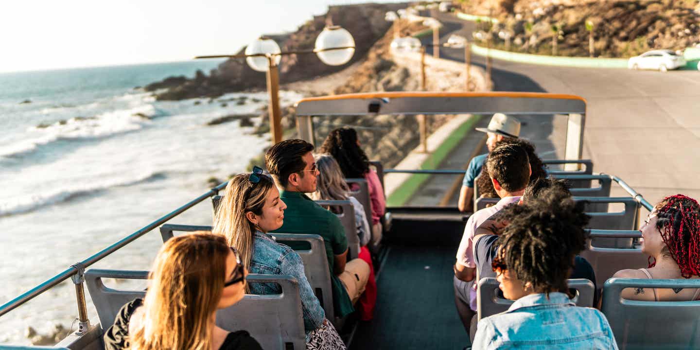 Eine Reisegruppe an Bord eines oben offenen Busses