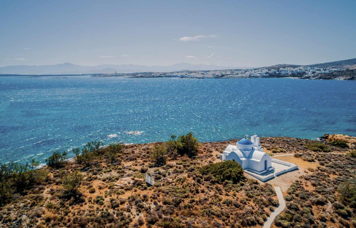 Paros Urlaub mit DERTOUR. Orthodoxe Kirche auf einem Hügel von Paros mit Meer im Hintergrund