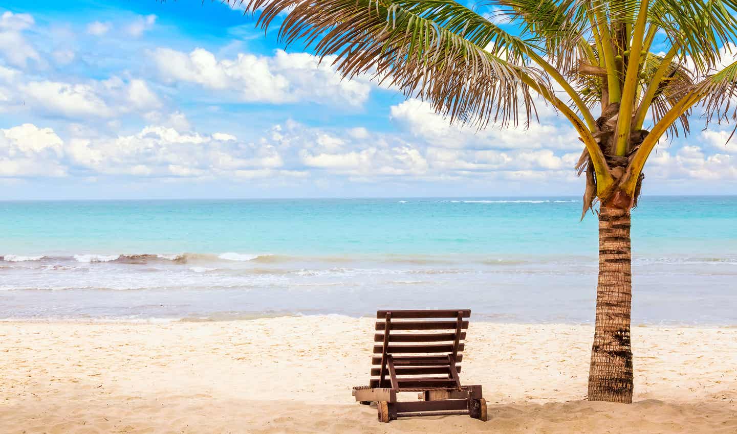 Kenia beste Reisezeit. Sonnenliege unter Palmen am Sandstrand