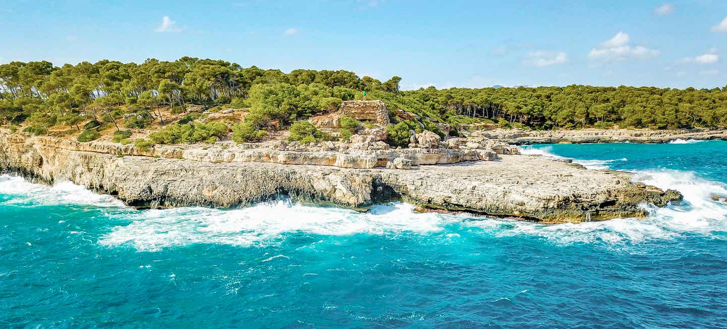 Klippen und Bucht bei Cala Mondragó auf Mallorca, mit türkisfarbenem Wasser und umgeben von Pinienwäldern und natürlicher Küstenlandschaft