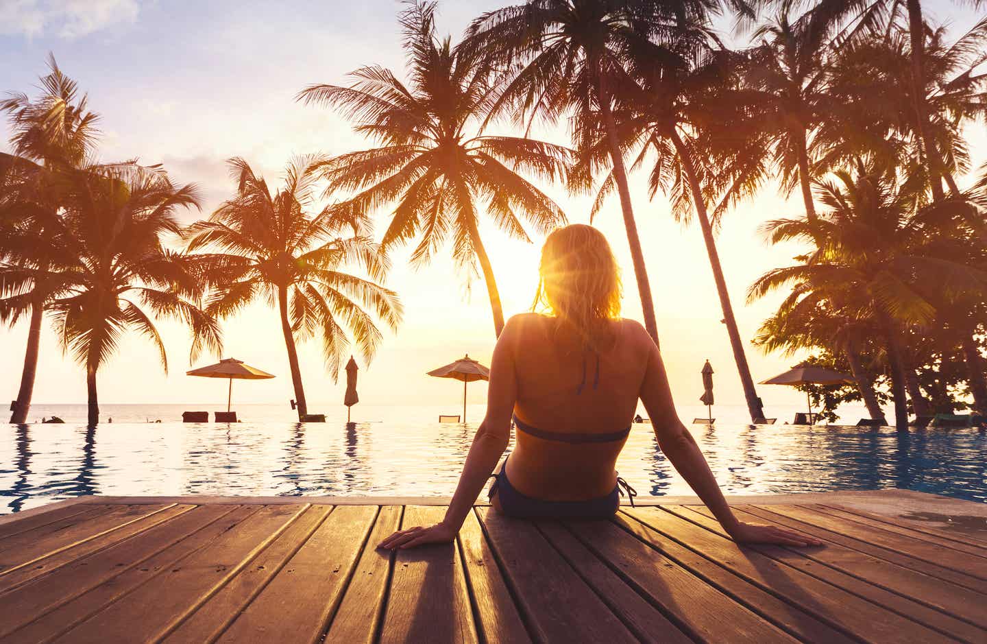 Am Strand entspannen in der besten Reisezeit in Pattaya - Frau sitzt am Pool unter Palmen