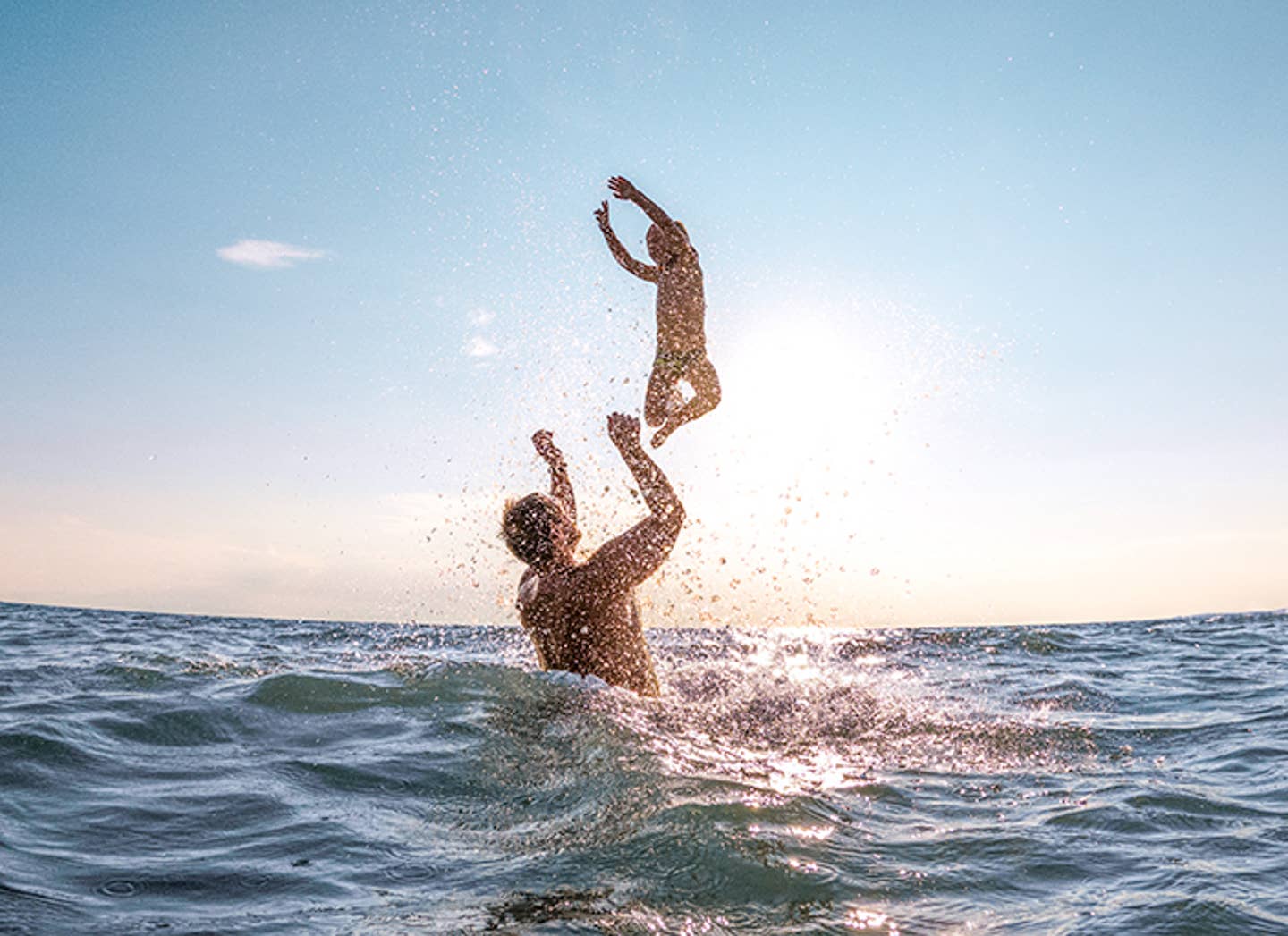 Vater mit Kind im Meer vor Sonne im Familienurlaub Vater mit Kind im Meer vor Sonne im Familienurlaub