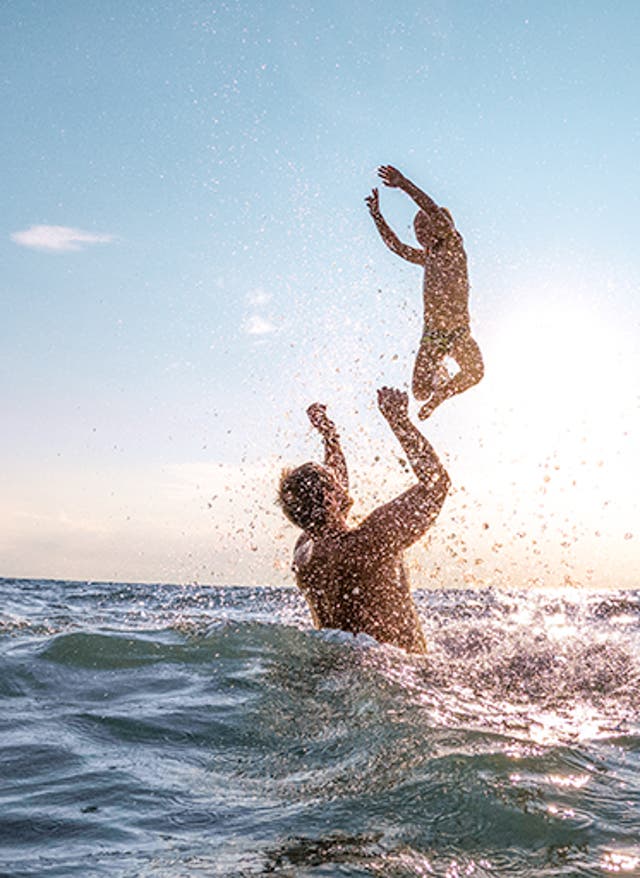 Familienurlaub Vater mit Kind im Meer vor Sonne im Familienurlaub