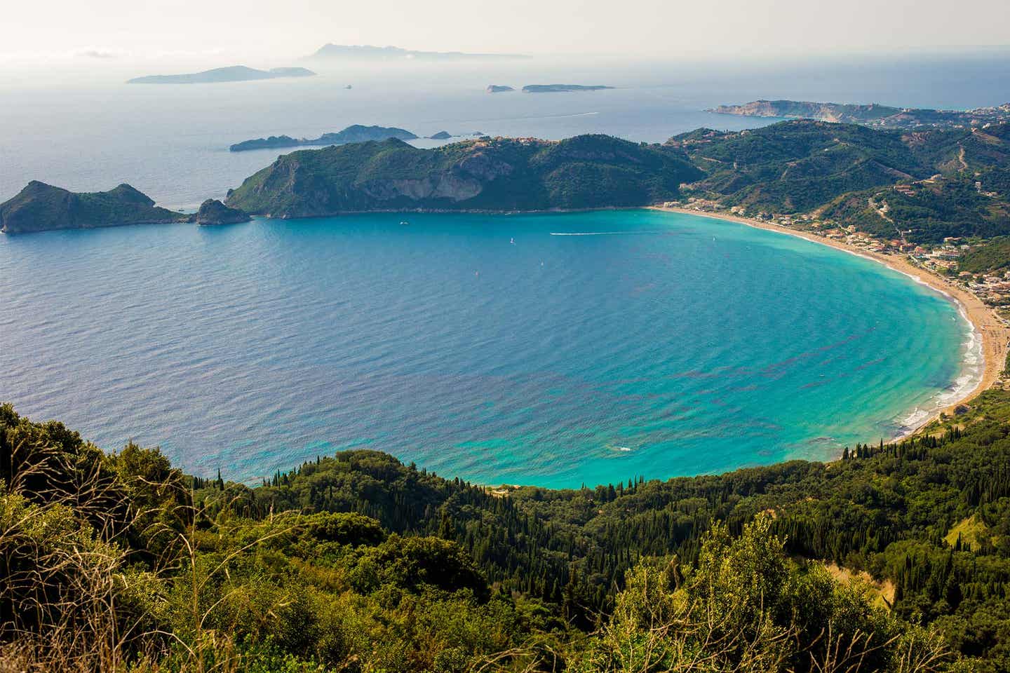 Blick auf den Strand in der Bucht von Agios Georgios umrandet von grüner Landschaft