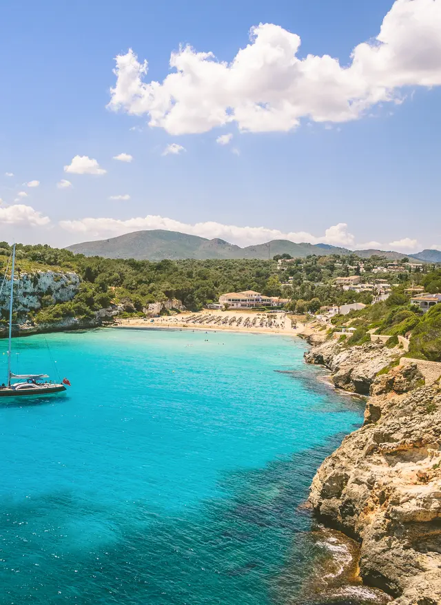Jetzt entdecken Mallorca-Urlaub am Strand von Estany, in der Bucht liegt ein einzelnes Segelboot