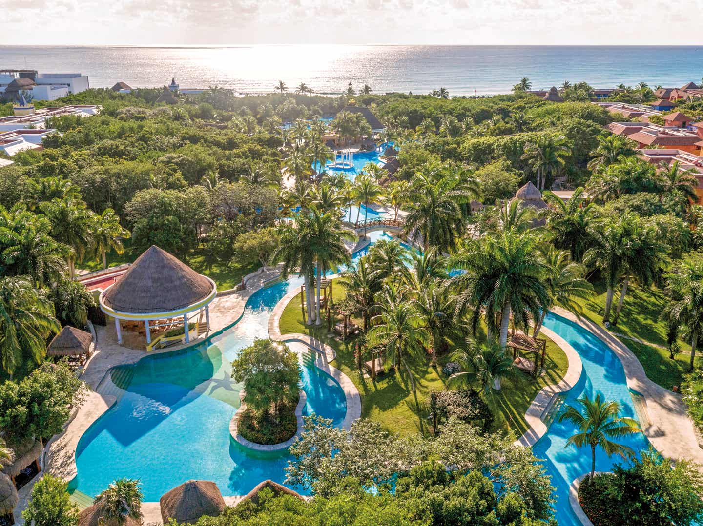 Blick auf die von Palmen gesäumte Poollandschaft des Iberostar Waves Paraiso Beach an der Riviera Maya in Mexiko