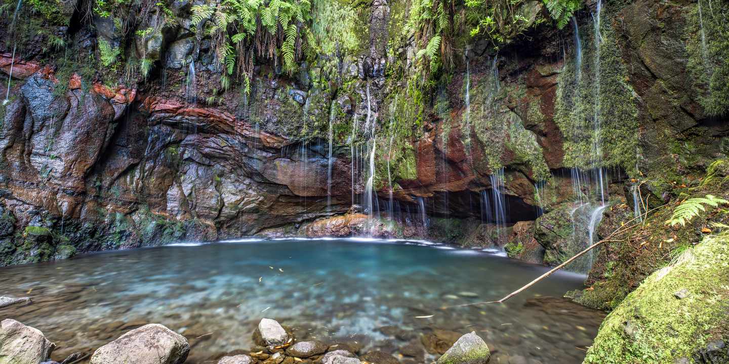 Wasserfall bei der Levada das 25 Fontes auf Madeira mit Felsen, Farnen und kleiner Lagune
