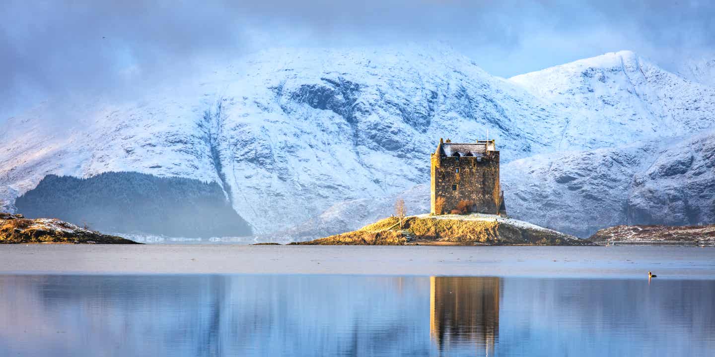 Blick auf ein Castle in Schottland an einem See in verschneiter Landschaft