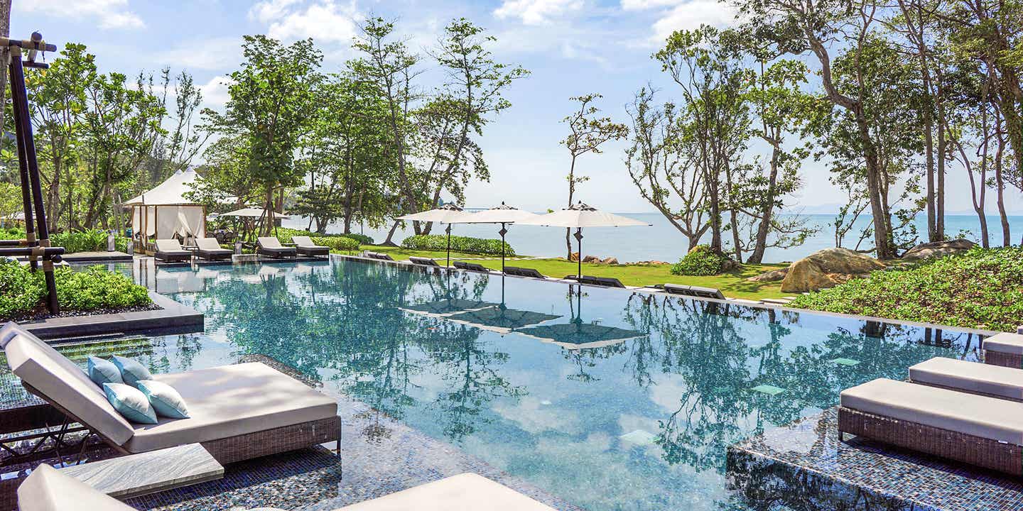 Ruhiger Pool mit Sonnenliegen in edlem Design mit Blick auf Ozean.