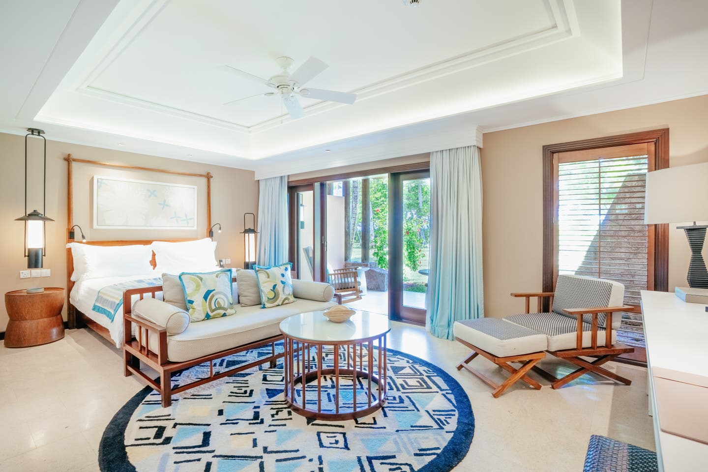 Blick durch eine Junior Suite mit komfortablem Doppelbett, Relaxliege und Gartenzugang.