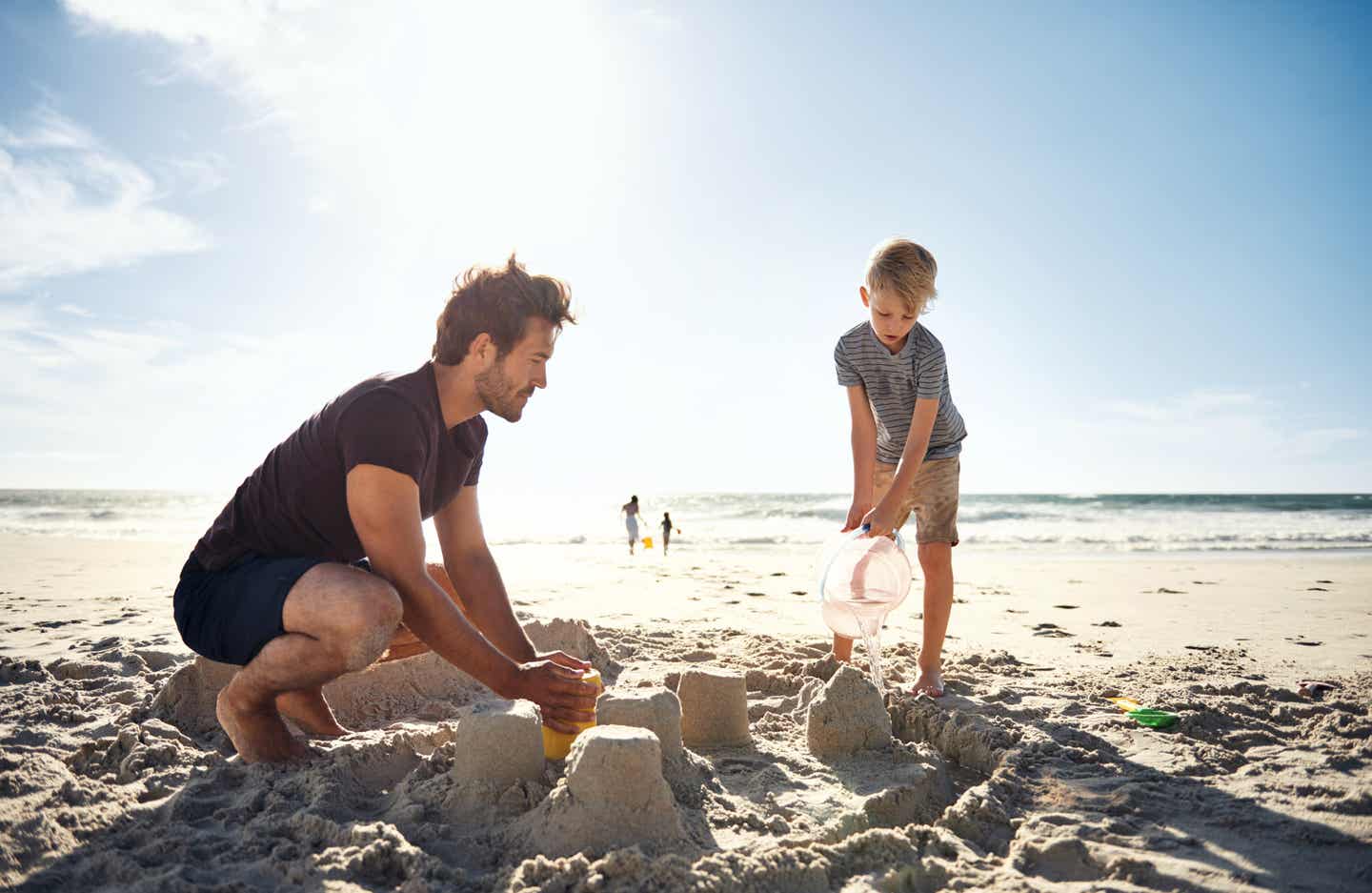 Ein Vater baut im Thassos-Urlaub mit seinem Sohn eine Sandburg am Strand