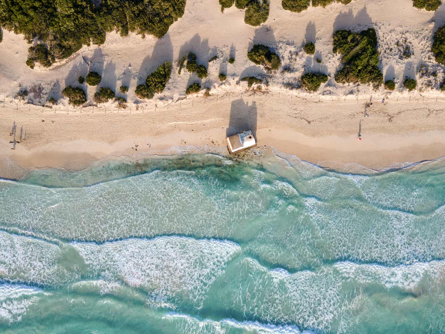 Luftaufnahme vom Es Trenc Beach, einer beliebten Mallorca-Sehenswürdigkeit, mit klarem Wasser, weißem Sandstrand und grüner Vegetation