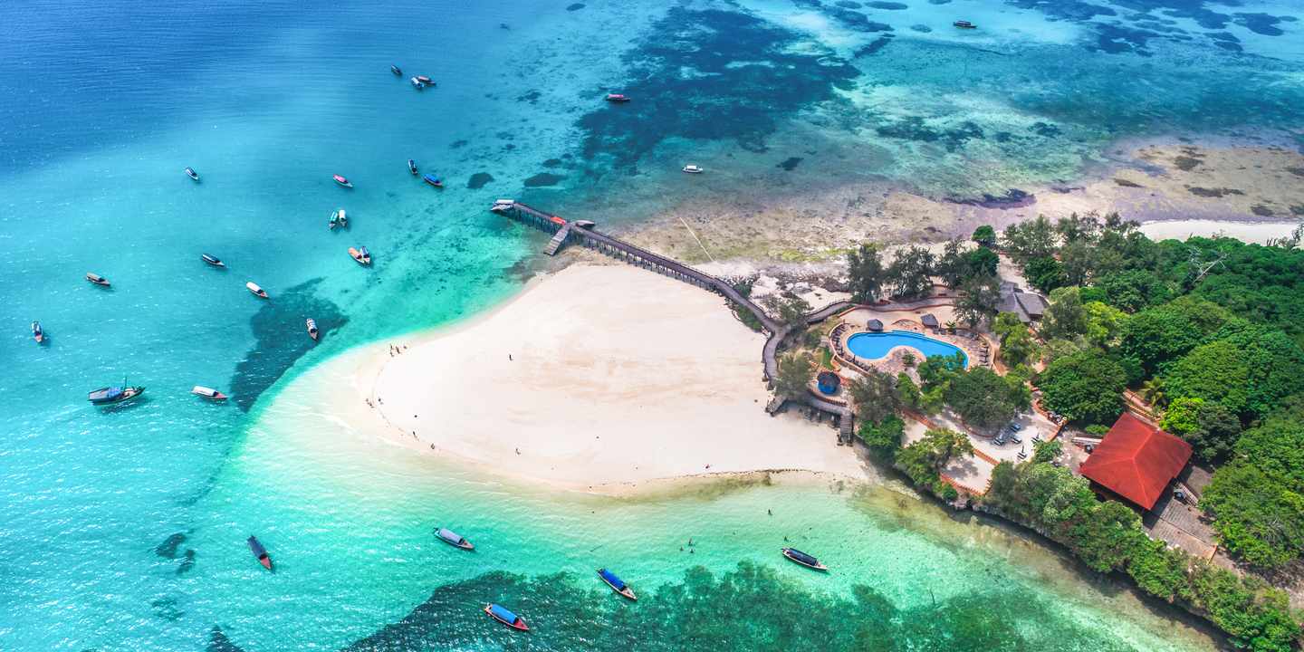 Luftaufnahme von Prison Island vor Sansibar mit heller Sandbank, Steg, Booten im klaren Wasser