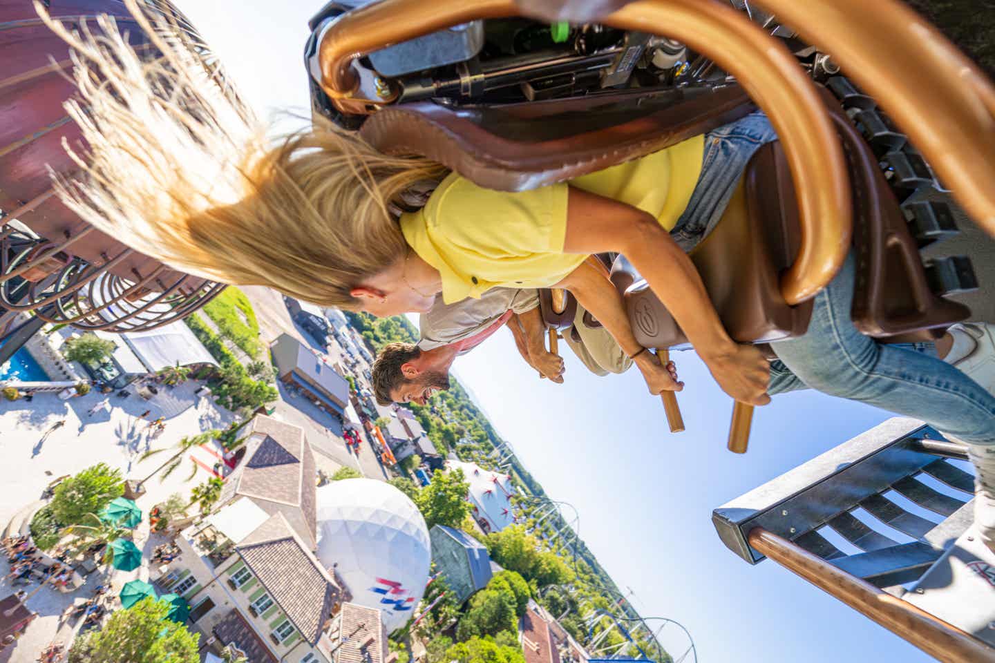 Blick auf Personen die in einer Achterbahn überkopf hängen