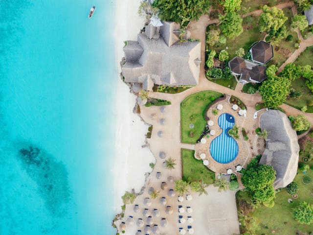 Luftbild des Hotels mit Pool, Strand und Unterkünften vor türkisblauem Meer