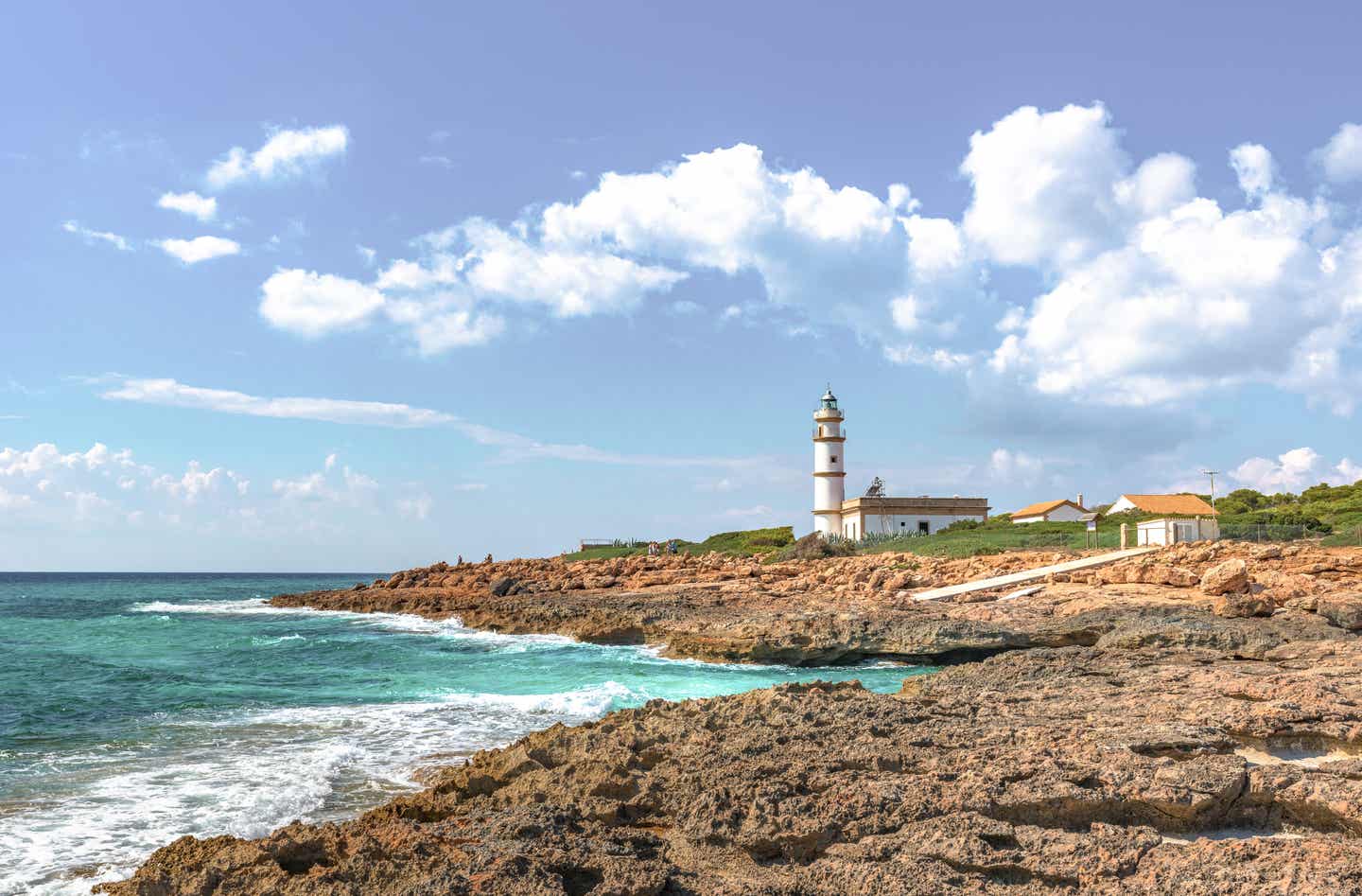 Türkisblaues Meer umgibt einen Felsen auf dem ein weißer Leuchtturm steht