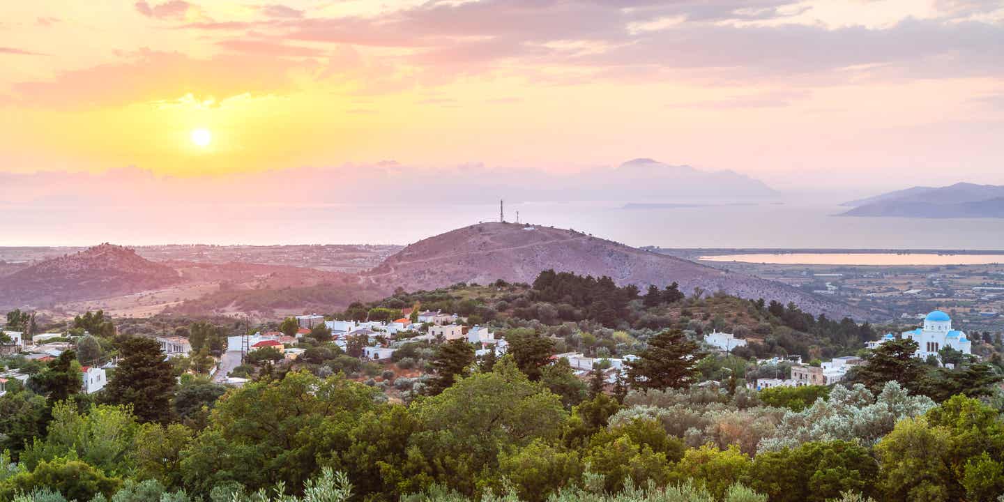 Instagram-Spot auf den griechischen Inseln: Zia auf Kos mit Blick über Olivenhaine und Meer bei Sonnenuntergang im warmen Abendlicht