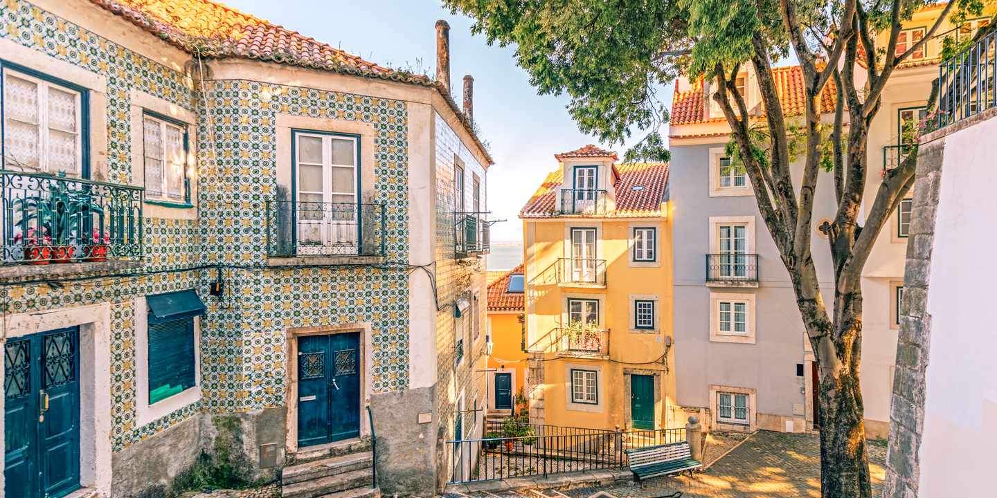 Enge Gasse in Alfama mit Azulejo-Fassaden und Treppen, typisches Straßenbild im ältesten Viertel Lissabons