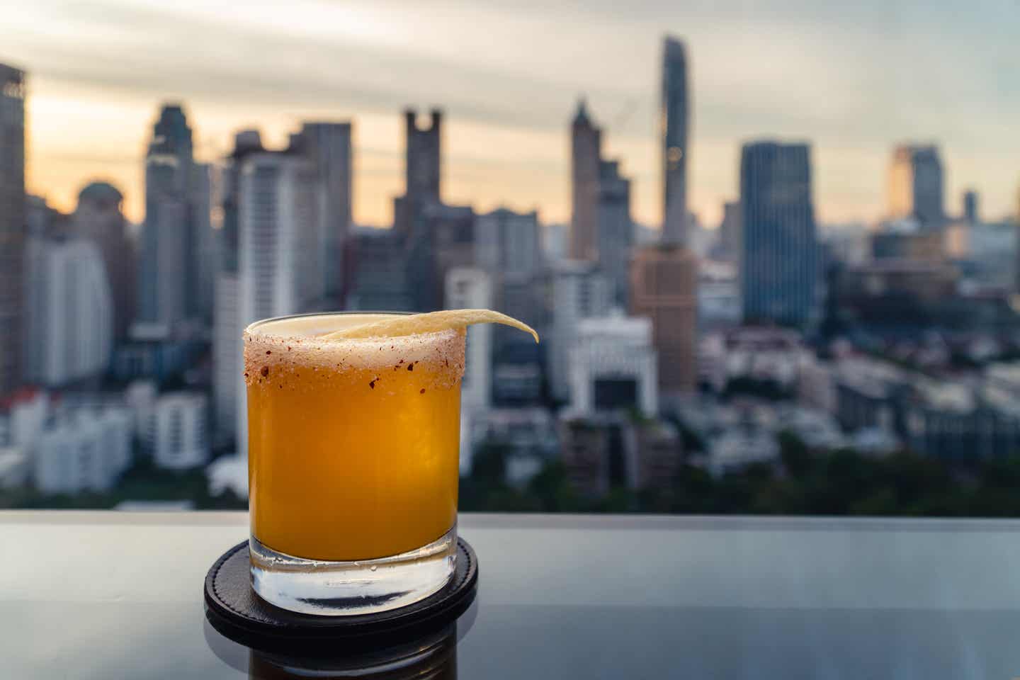 Cocktail auf einem Tisch vor dem Panorama Bangkoks