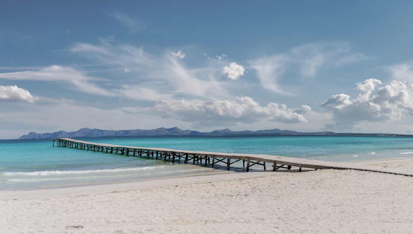 Playa de Muro Urlaub mit DERTOUR. Langer Steg ins türkisblaue Meer in Platja de Muro in der Bucht von Alcudia