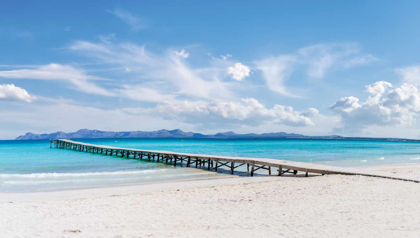 Playa de Muro Urlaub mit DERTOUR. Langer Steg ins türkisblaue Meer in Platja de Muro in der Bucht von Alcudia