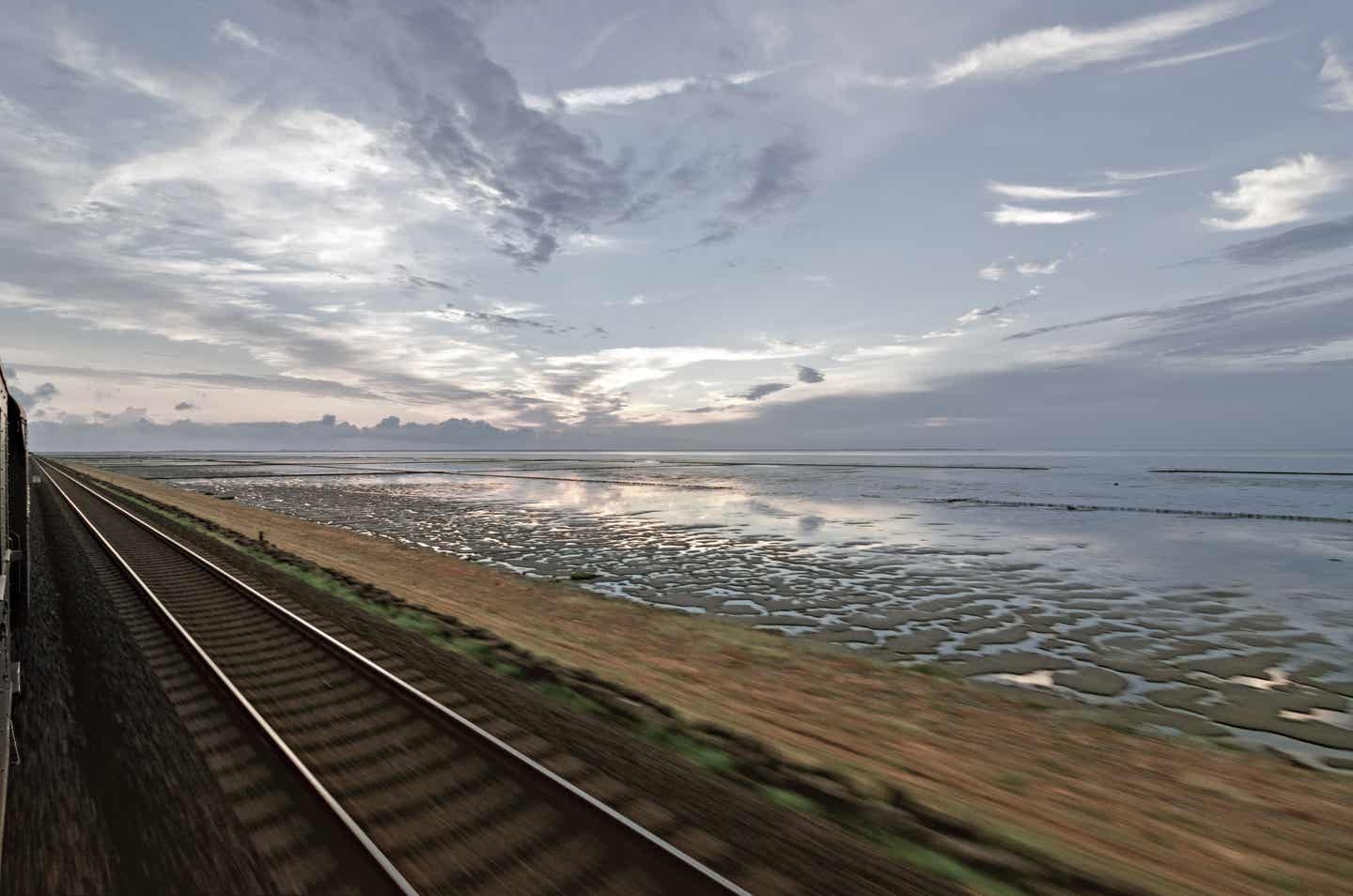 Sylt Urlaub mit DERTOUR. Blick aus dem Zug auf das Wattenmeer bei einer Fahrt über den Hindenburgdamm