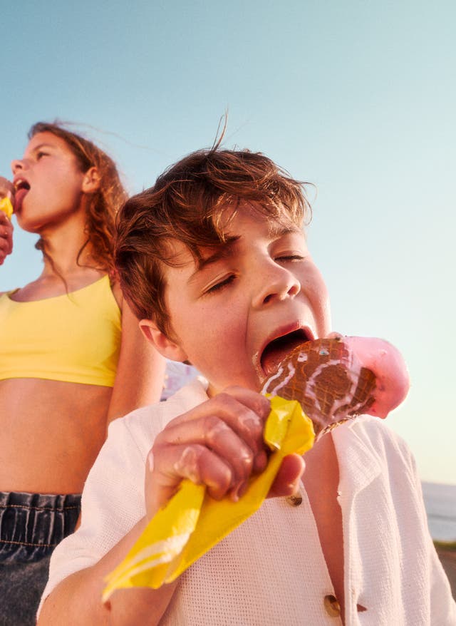 Familienurlaub Zwei Kinder essen im Familienurlaub ein Eis am Strand