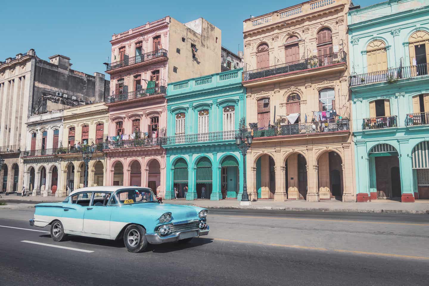 Havanna als Herbstferien Reiseziel: Blauer Oldtimer vor bunten Häusern in der Downtown Street in Old Havanna