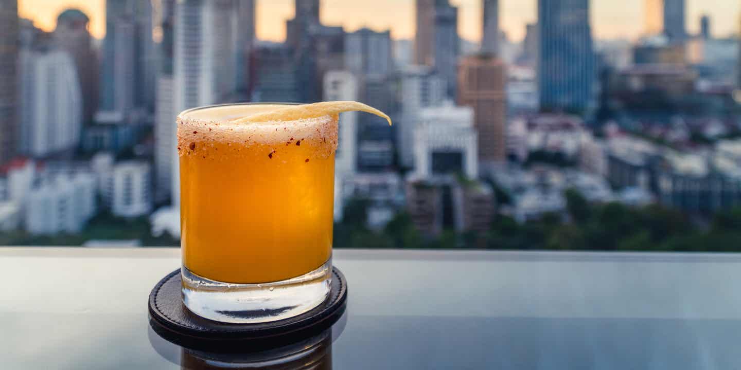 Cocktail auf einem Tisch vor dem Panorama Bangkoks