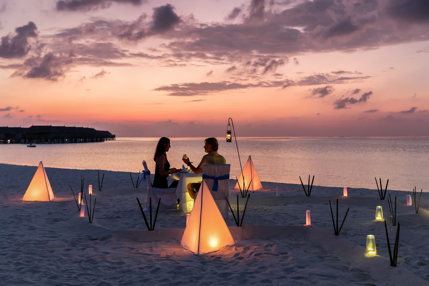 Pärchen genießt den Sonnenuntergang am Strand von dem Malediven bei einem Abendessen