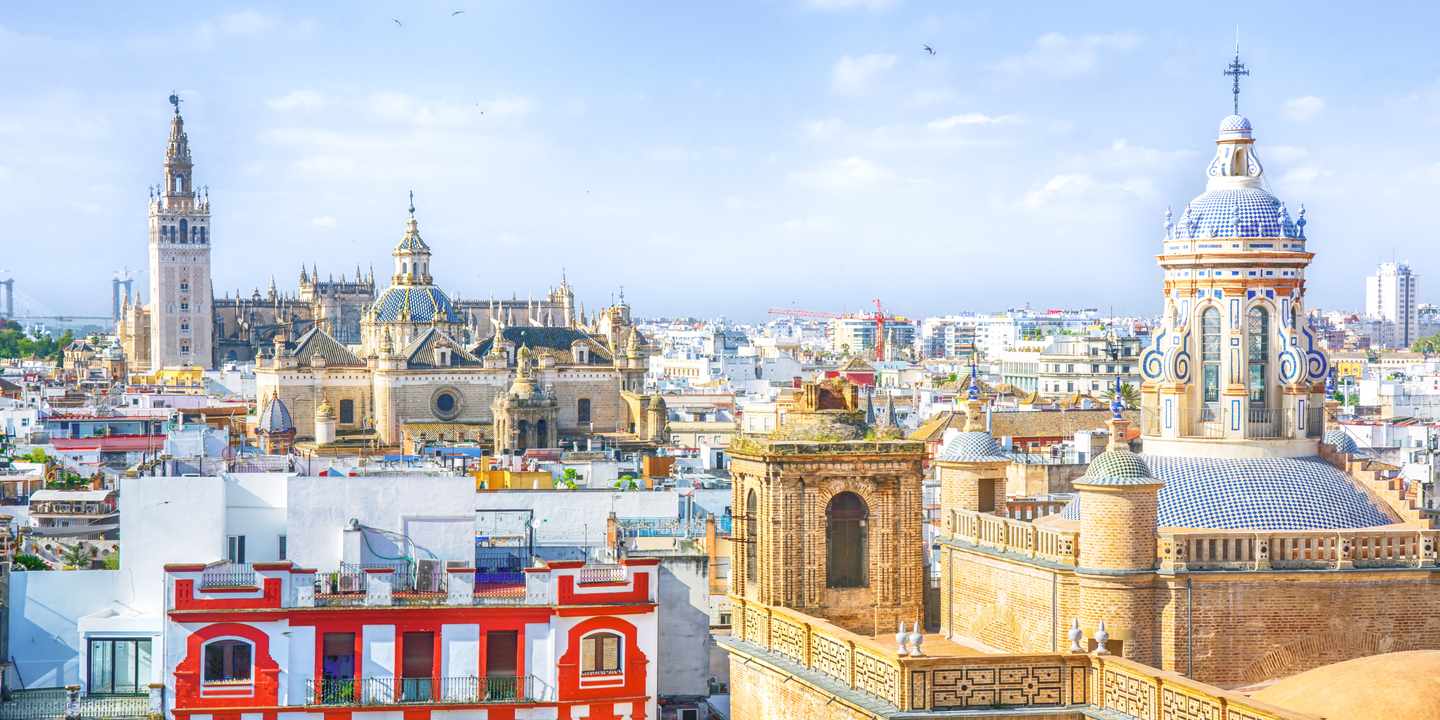 Panoramablick über Sevilla mit Kathedrale, Giralda und farbigen Altstadtdächern unter klarem Himmel